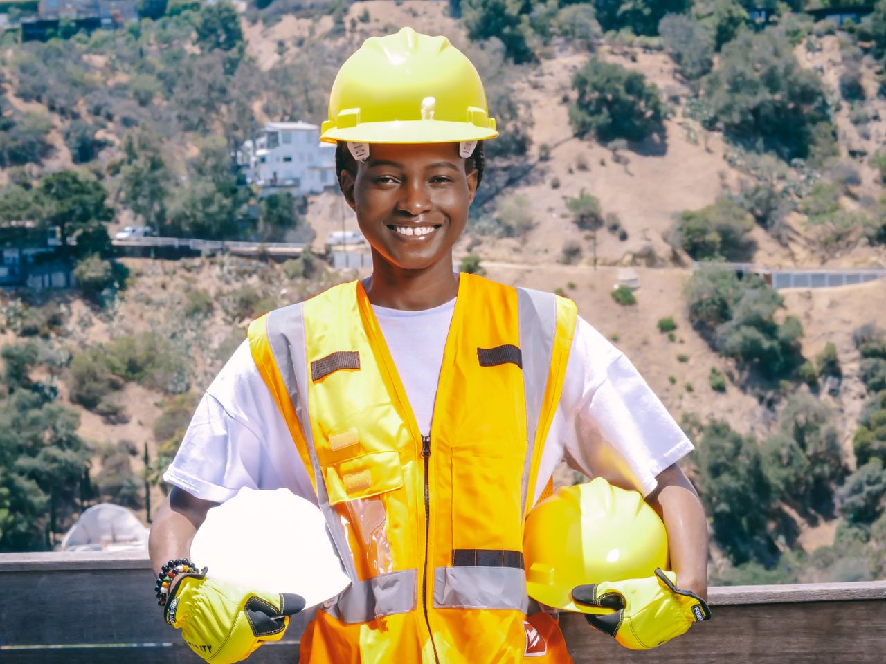 Outdoor portrait of an engineer smiling in safety gear, showcasing PPE essentials.